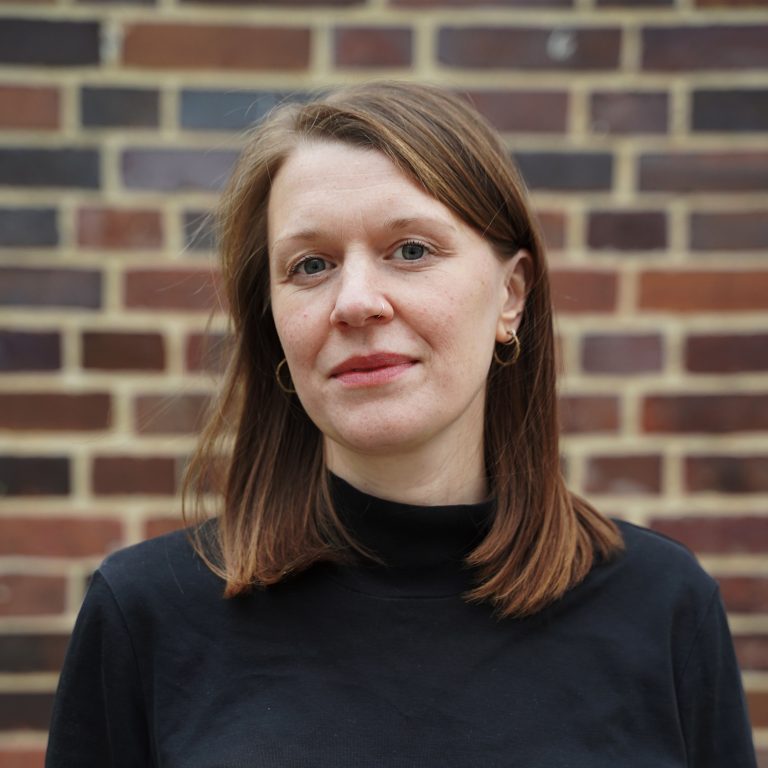 Portrait photo of Lia Polotzek: A woman with shoulder-length brown hair wearing a black top.