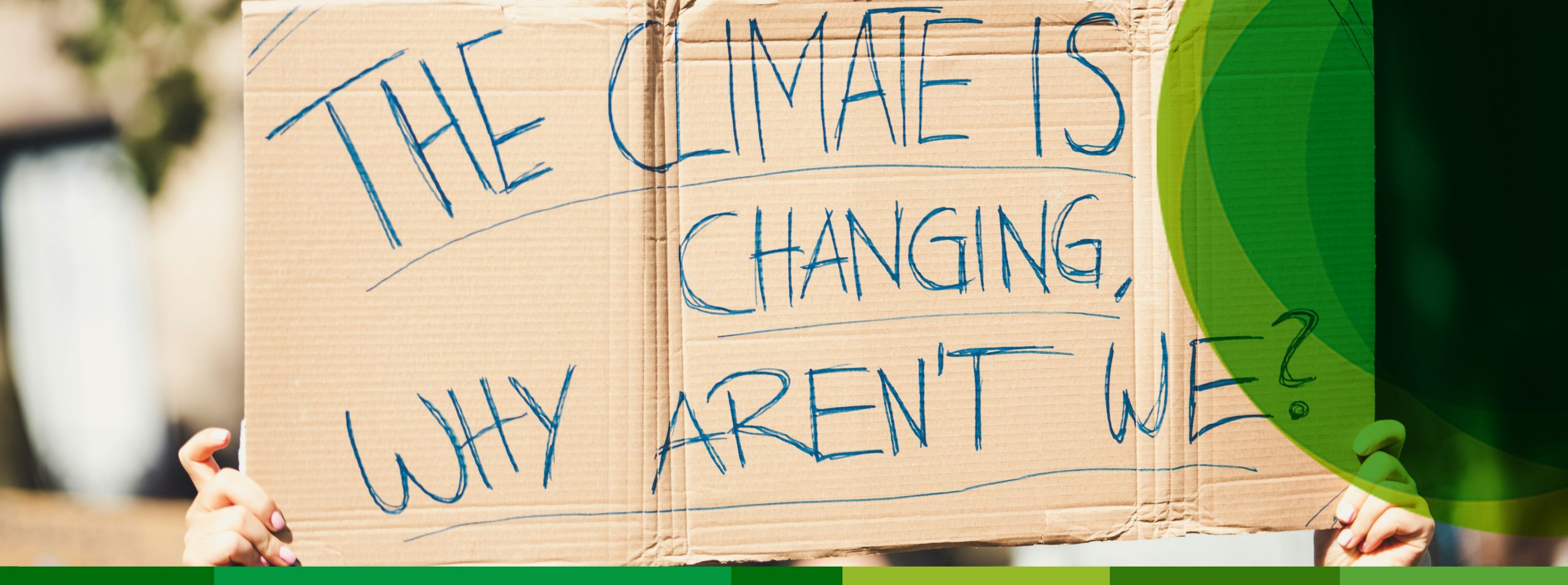 Jeman hält ein Pappschild hoch mit der Aufschrift "The Climate is Changing, why aren't we?"