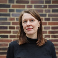 Portrait photo of Lia Polotzek: A woman with shoulder-length brown hair wearing a black top.