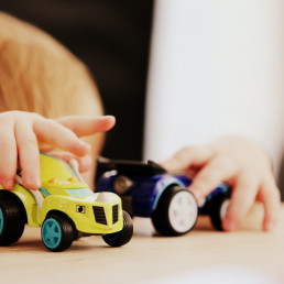 Ein Kleinkind spielt mit zwei Plastikautos.